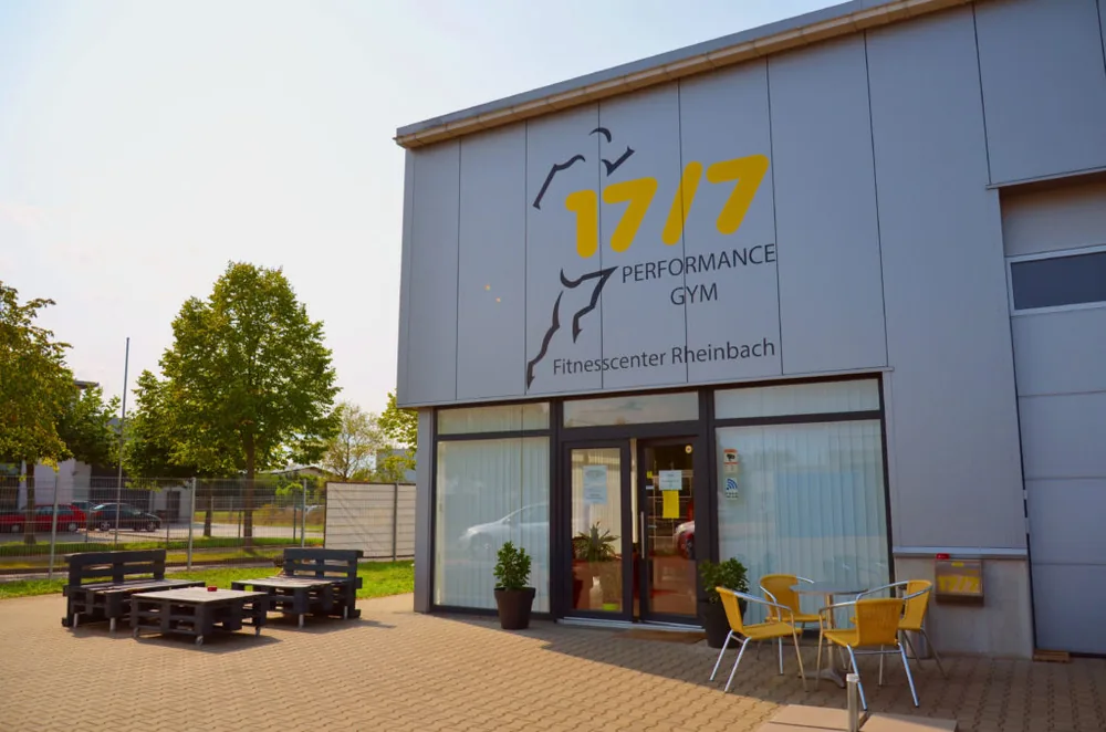 Außenansicht des 17/7 Performance Gym mit Eingang und Sitzbereich.
